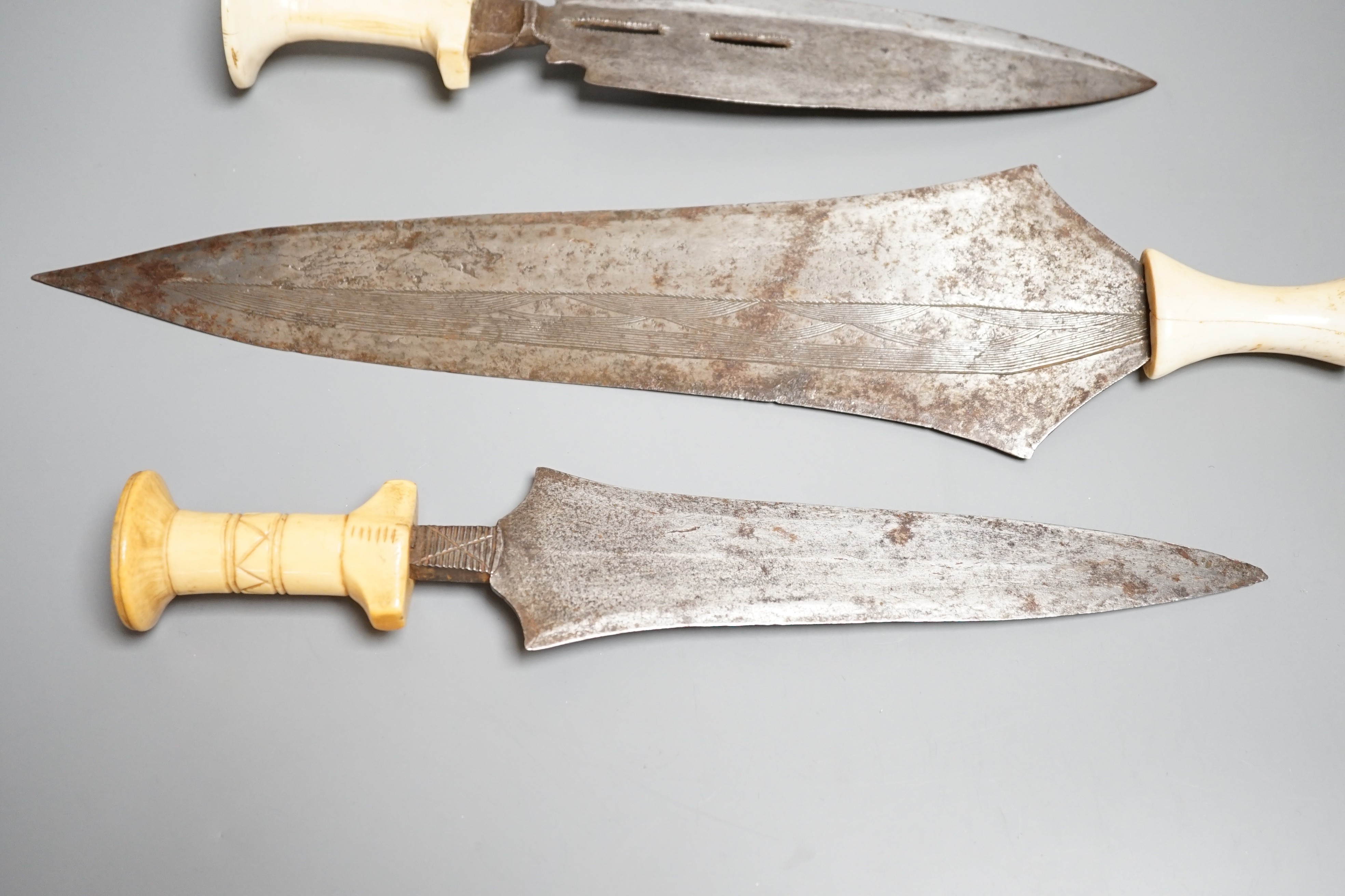 Three assorted African tribal daggers c.1900, each with ivory handle including two with decorated blades and one with iron pommel, maximum 40cms